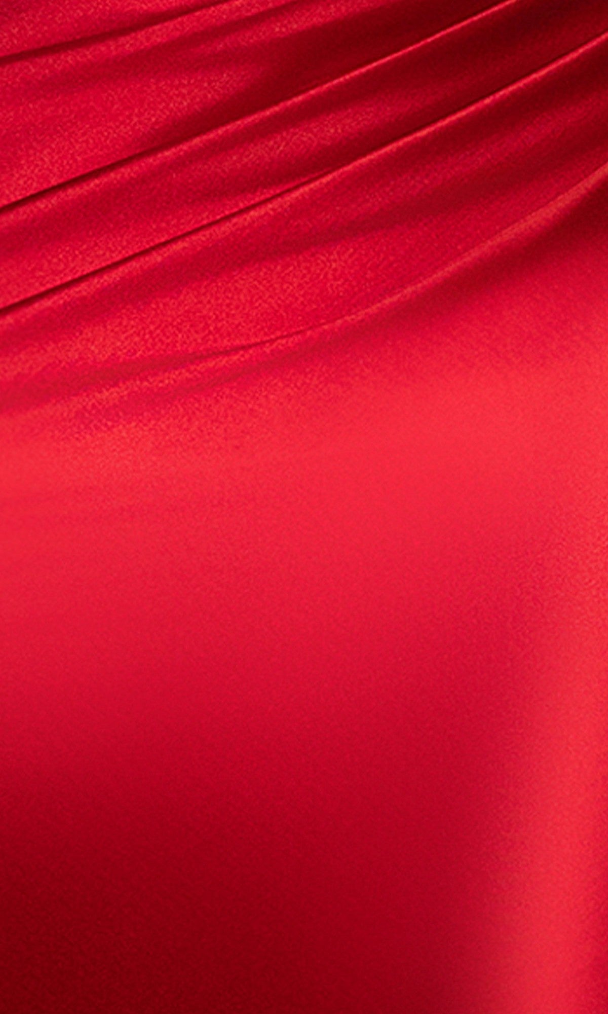 A close-up of smooth, shiny red fabric with diagonal folds and a silky texture, reminiscent of the Blondie Nites 5946BN Long Prom Dress with its fitted skirt and elegant corset bodice.